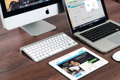 Un ordinateur de bureau, un ordinateur portable et une tablette posés sur un bureau.